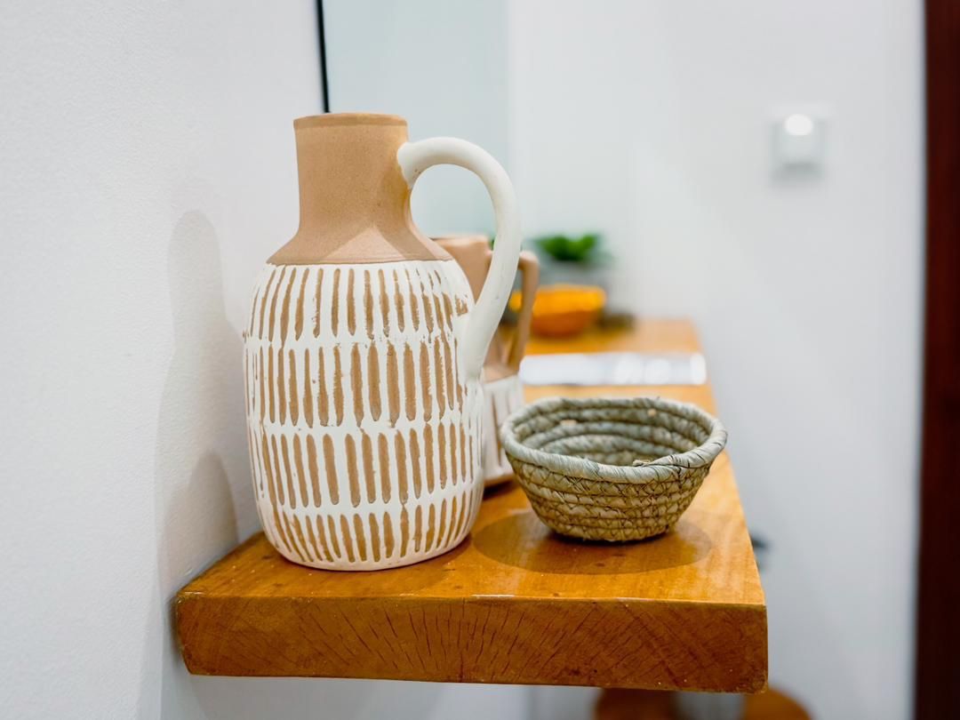 Carafe en céramique et panier tressé posés sur une table en bois à l'arrivée