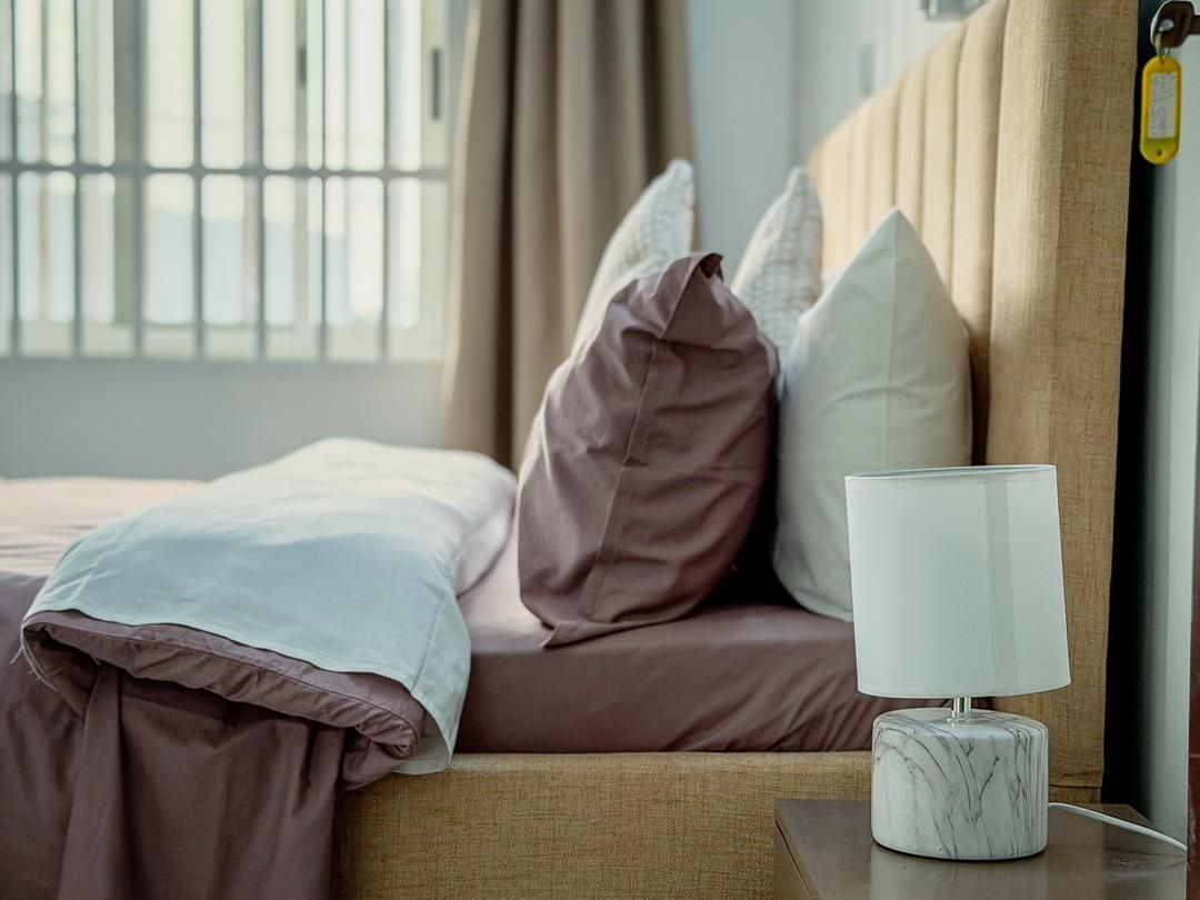 Lit préparé avec linge de maison et lampe de chevet